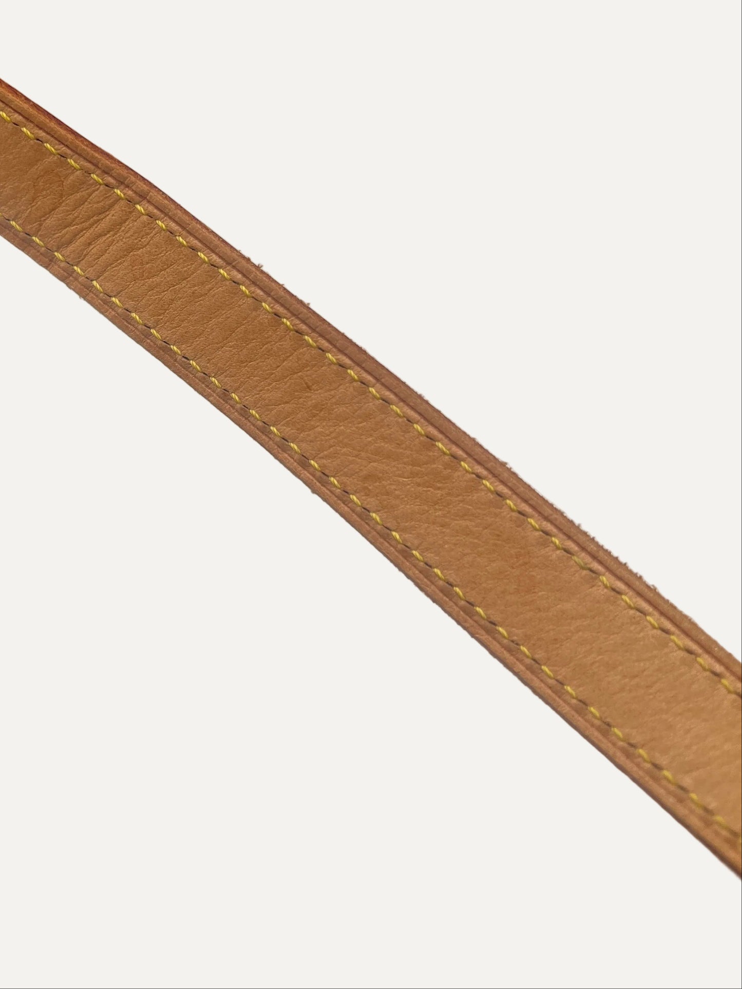 Close-up of a brown leather handbag with visible stitching on a white background