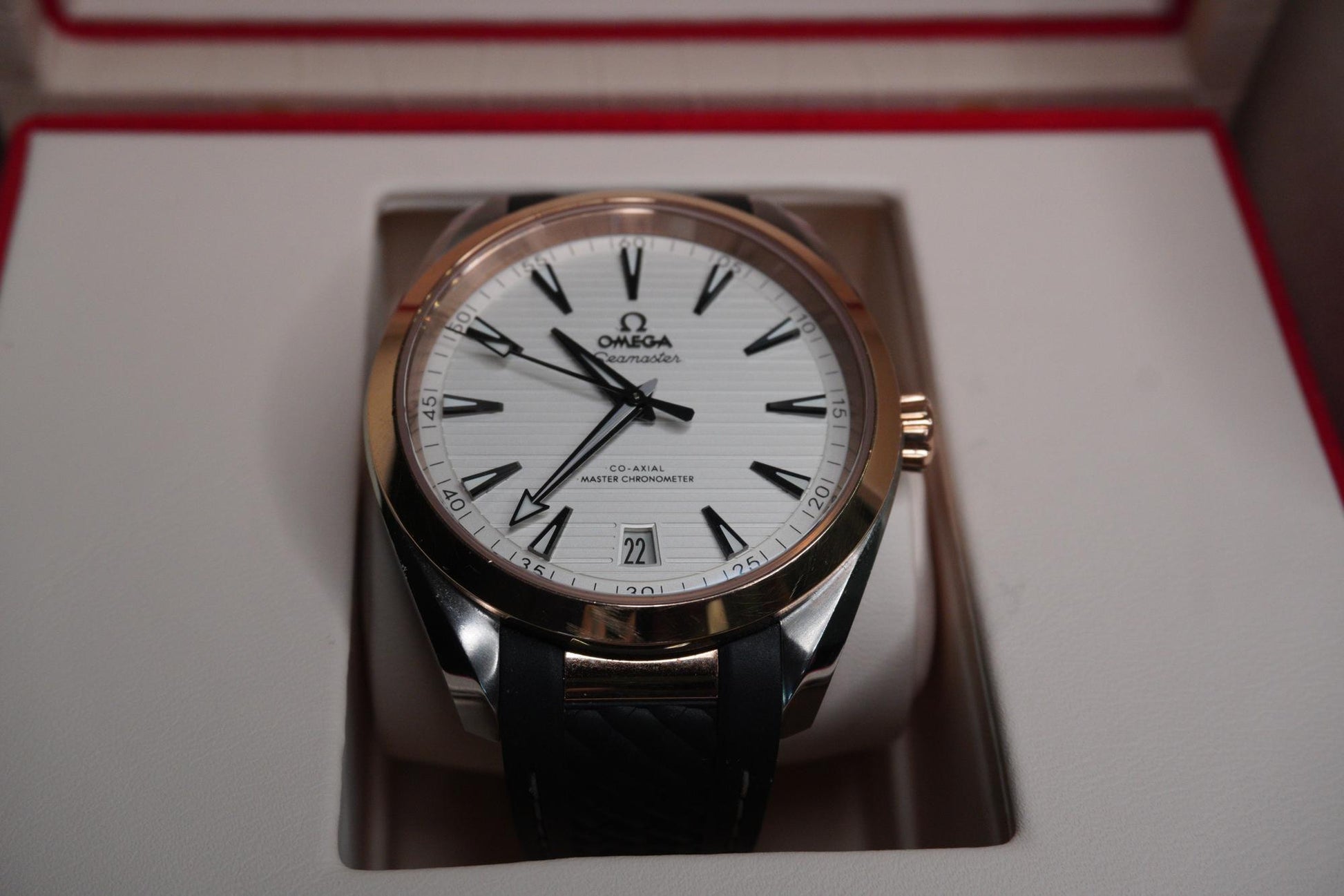 Omega watch with white face and black leather strap on a reflective surface