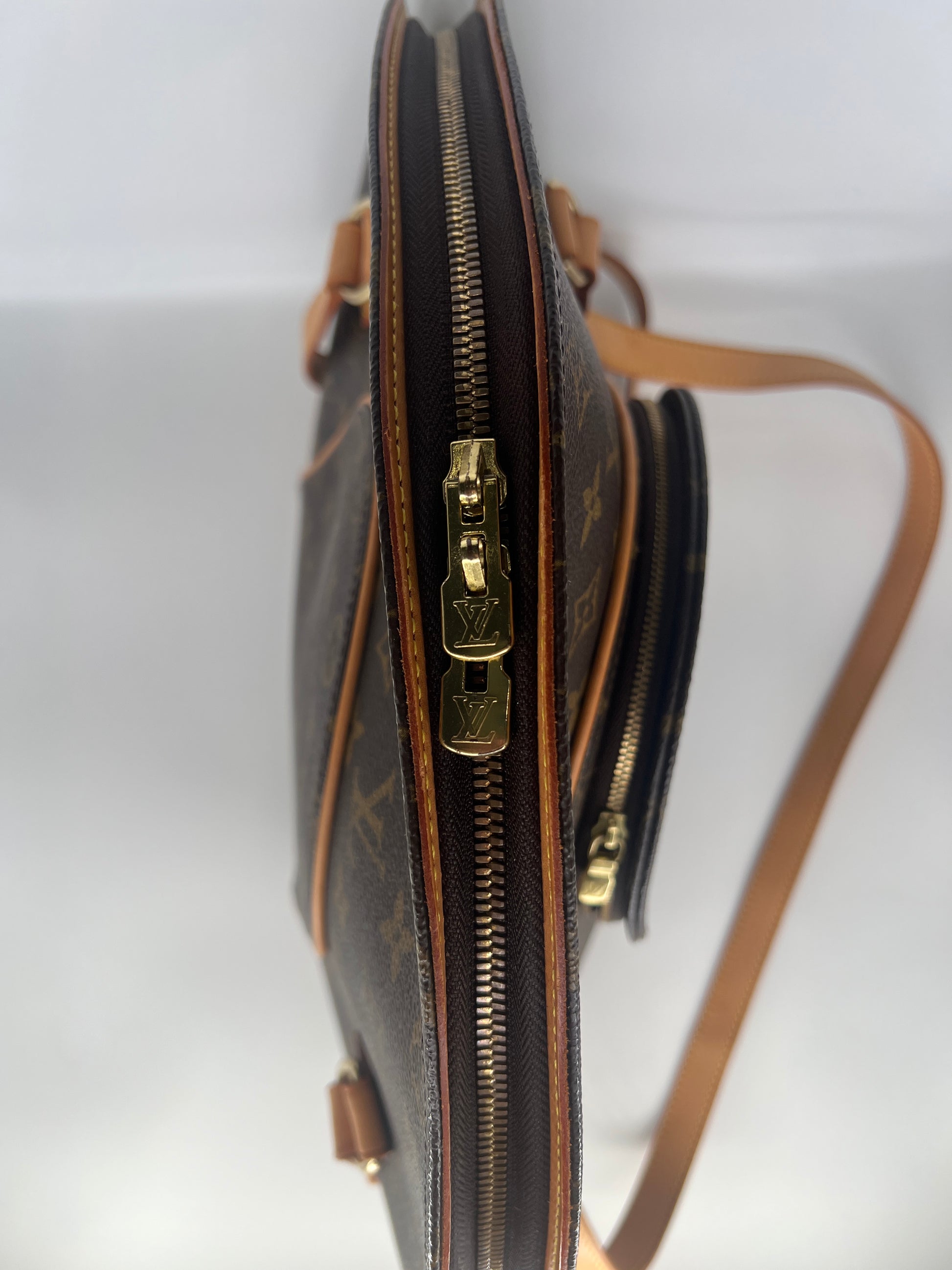 Close-up of a brown leather handbag with gold zipper on a white background