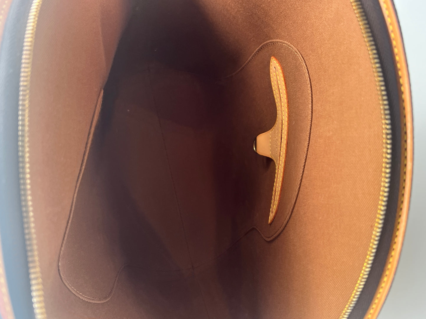 Close-up of a brown leather product with a visible brand logo on a gray background