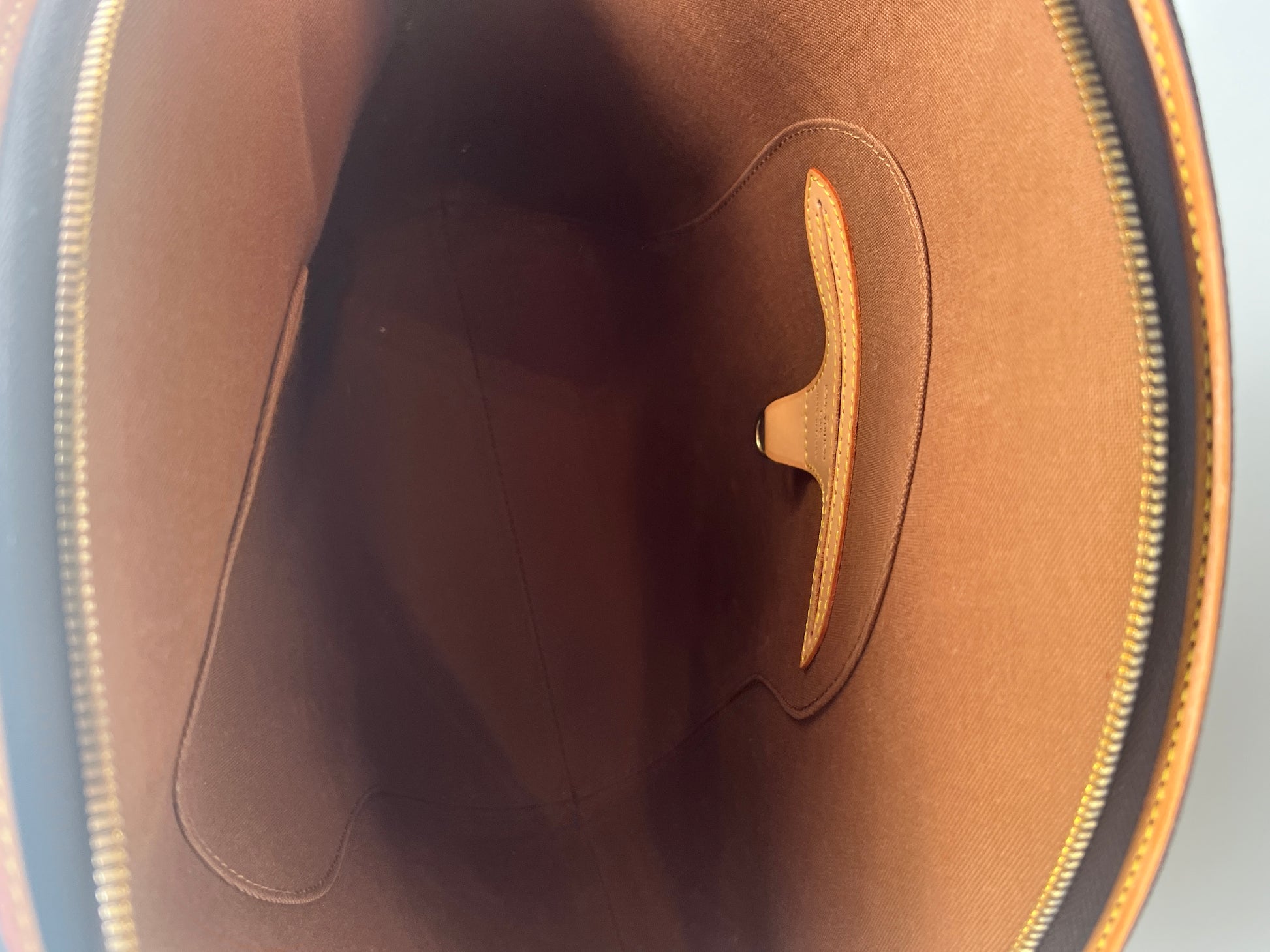Close-up of a brown leather product with a visible brand logo on a gray background